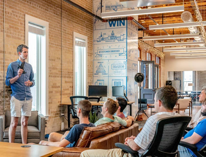 Operations manager of a startup company conducting a briefing regarding updates on the company's policies while the rest of the team looks on