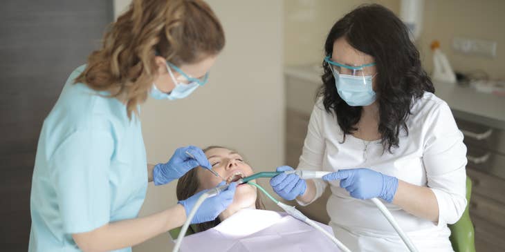 Orthodontic dental assistant keeping patients’ mouths dry by using a suction hose.
