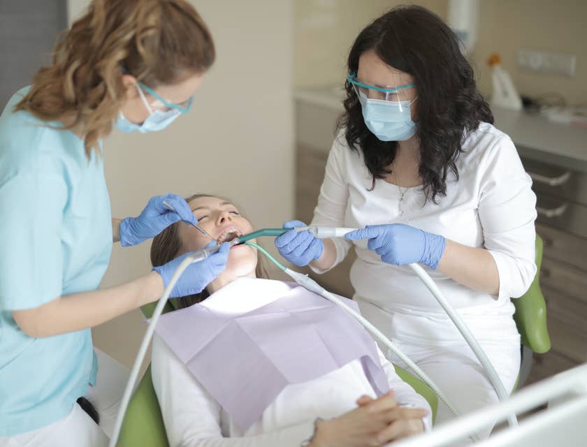 Orthodontic dental assistant keeping patients’ mouths dry by using a suction hose.