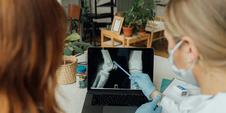 An orthopedic doctor showing an x-ray result to a patient.