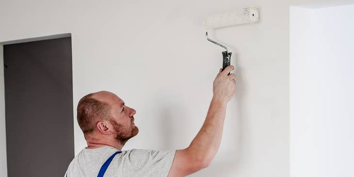 Painter painting a wall with a roller.