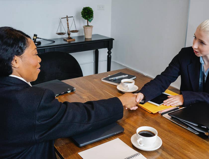 A female patent lawyer shaking hands with a female client after having a meeting and providing assistance.