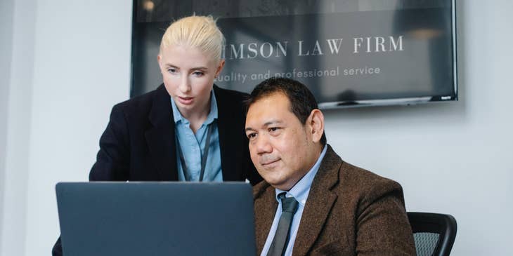 A female patent paralegal reporting and working beside an attorney in a law firm.