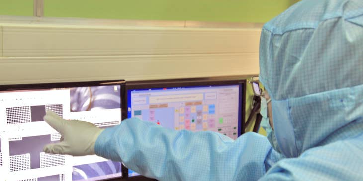 Patient care coordinator checks the schedule of the care team on a computer in a full protective suit.