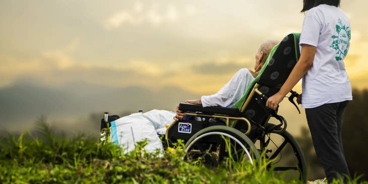 Patient sitter assists the patient in a wheelchair as they went out for a stroll.