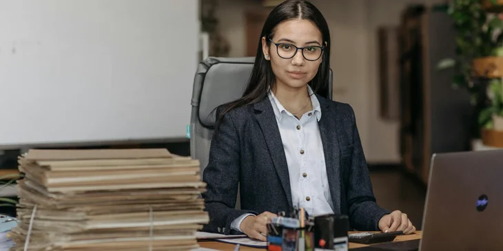 A payroll director in an office in front of a laptop.