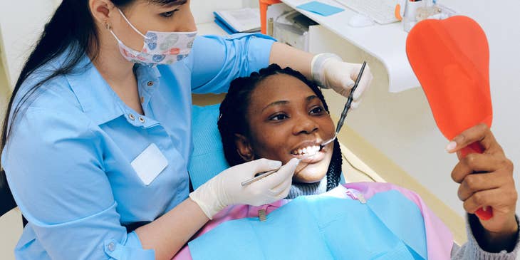Periodontist shows a patient results after dental treatment using a mirror.