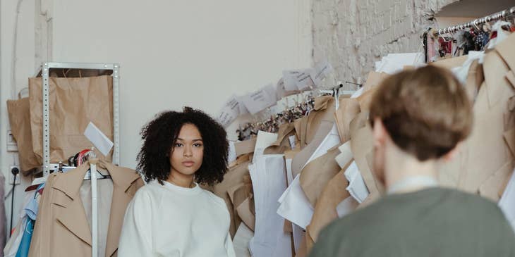 Personal stylist working with a female client with clothes racks behind her.