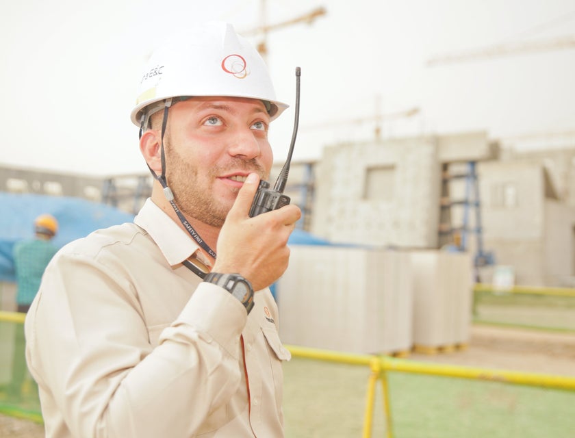 Petroleum engineer holding a wireless handset and wearing a hard hat while coordinating the location of extraction to his colleague