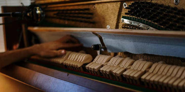 A piano tuner working on a grand piano.