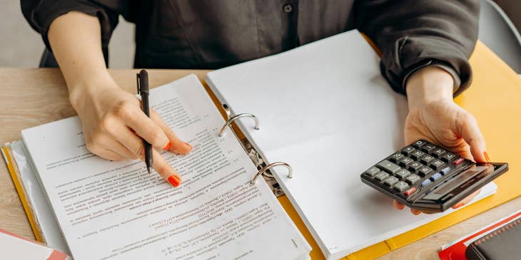 A person holding a calculator and pointing to part of the document.