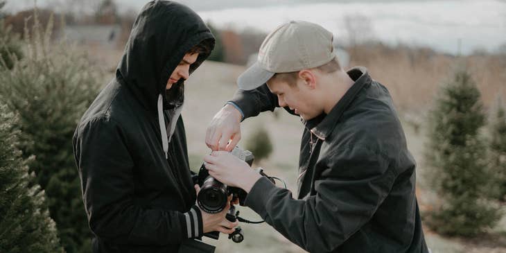 A photographer fixing his DSLR while his Photographer Assistant is holding it.
