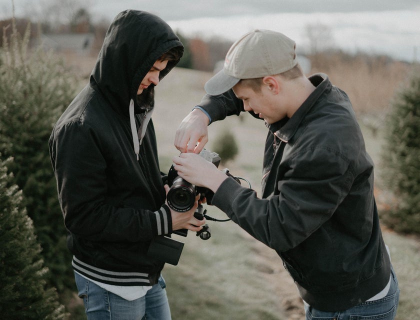 A photographer fixing his DSLR while his Photographer Assistant is holding it.