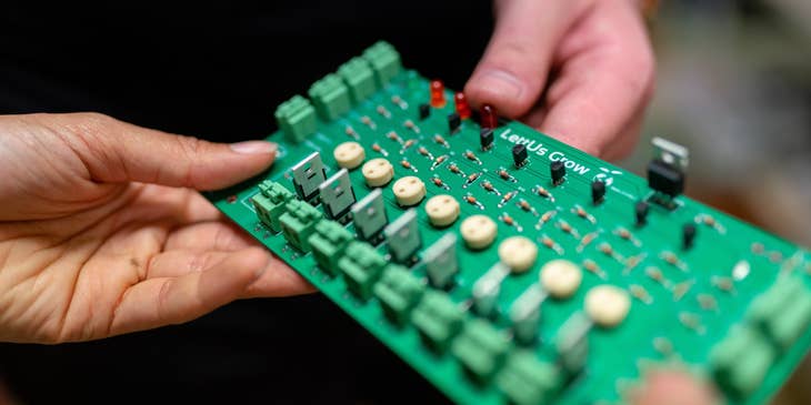 Physical design engineer holding a circuit board and showing to his colleague for further optimization.
