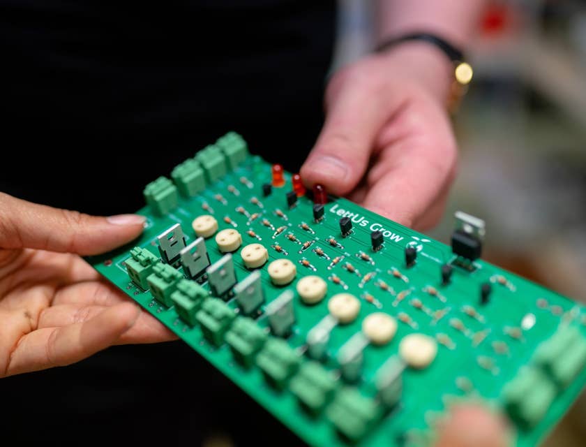 Physical design engineer holding a circuit board and showing to his colleague for further optimization