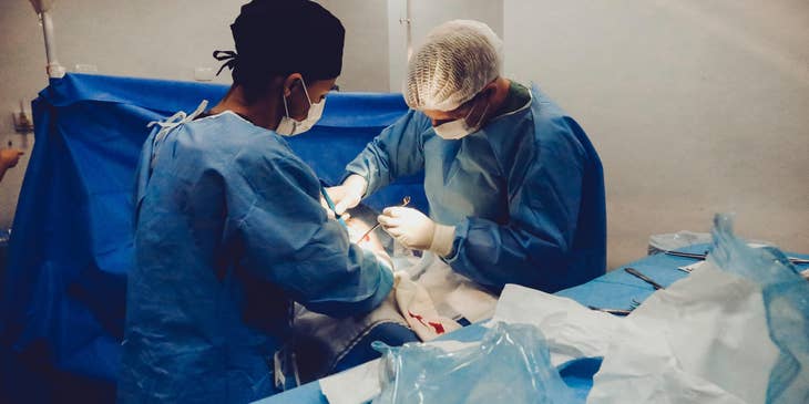 Physician assistant is supporting the doctor in a surgery.