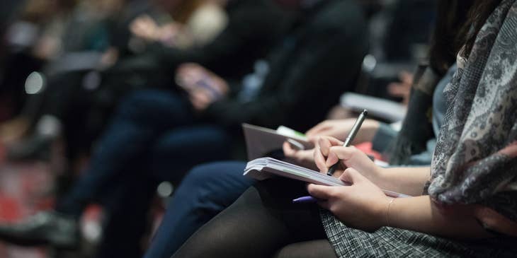 A physician recruiter taking down notes in a conference.