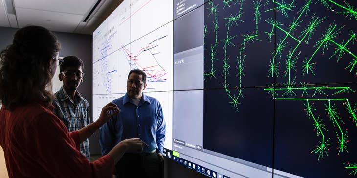 Planning engineer presenting an updated project timeline to the lead engineers while standing in front of the projected screen.