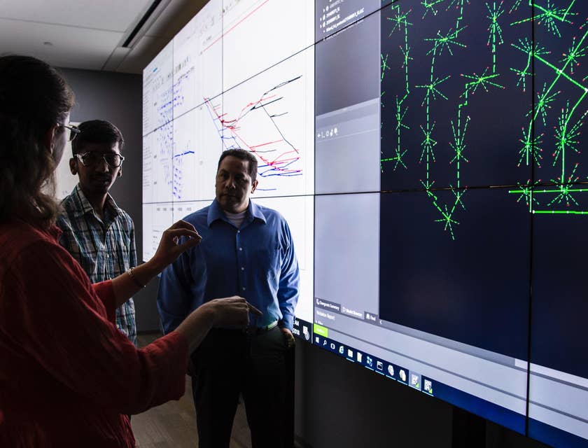 Planning engineer presenting an updated project timeline to the lead engineers while standing in front of the projected screen.