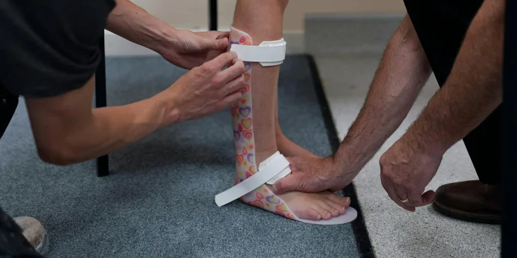 A podiatrist measures patients foot for a foot cast to treat a leg injury.