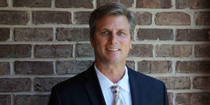 portrait of a portfolio manager wearing a business suit and smiling against a brick wall
