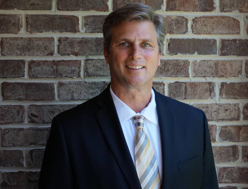 portrait of a portfolio manager wearing a business suit and smiling against a brick wall
