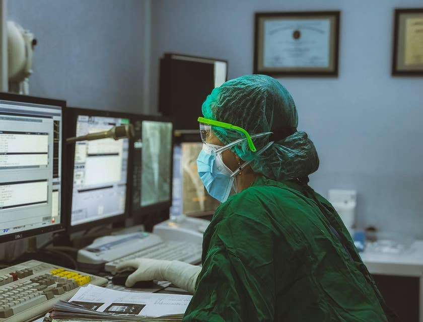 Practice manager in full PPE working on a desktop