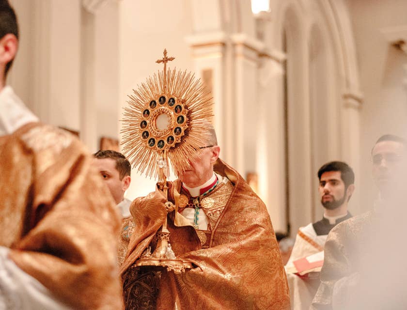 A priest holding the golden cross during the opening of the mass.