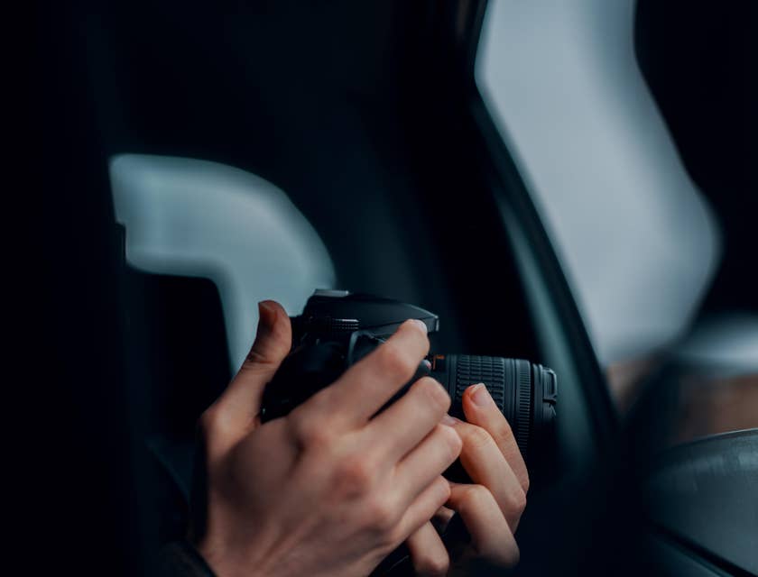A private investigator working undercover doing surveillance and taking photos inside a vehicle.