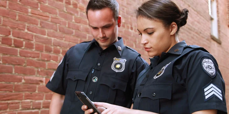 Two probation officers standing outside a property looking at a phone and about to check on probationer.