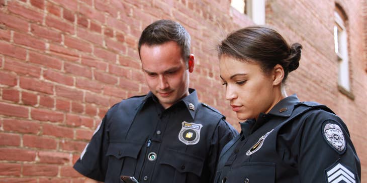 Two probation officers standing outside a property looking at a phone and about to check on probationer.