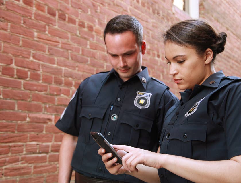 Two probation officers standing outside a property looking at a phone and about to check on probationer.