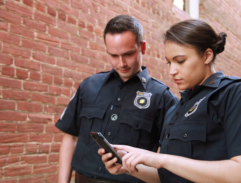Two probation officers standing outside a property looking at a phone and about to check on probationer.