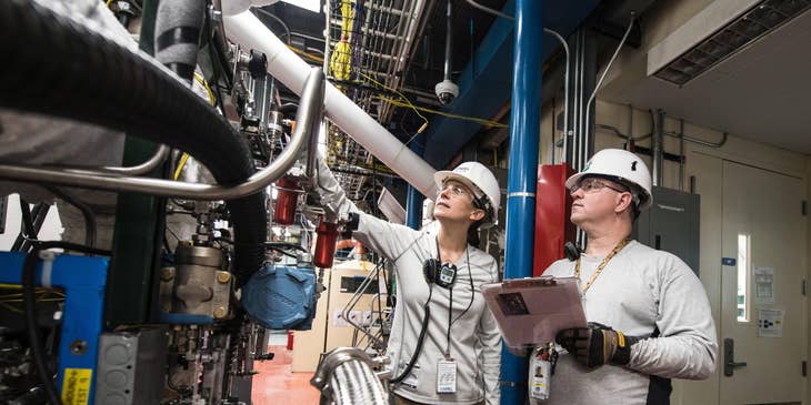 Process control engineer checking the machinery with a technician at a manufacturing facility.