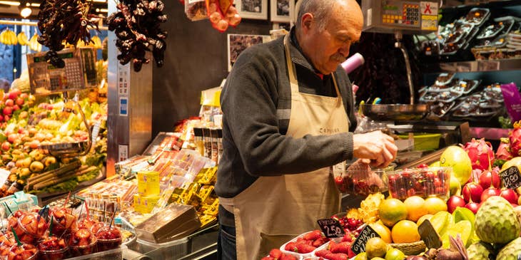 Produce clerk arranging the produce on a transparent container.