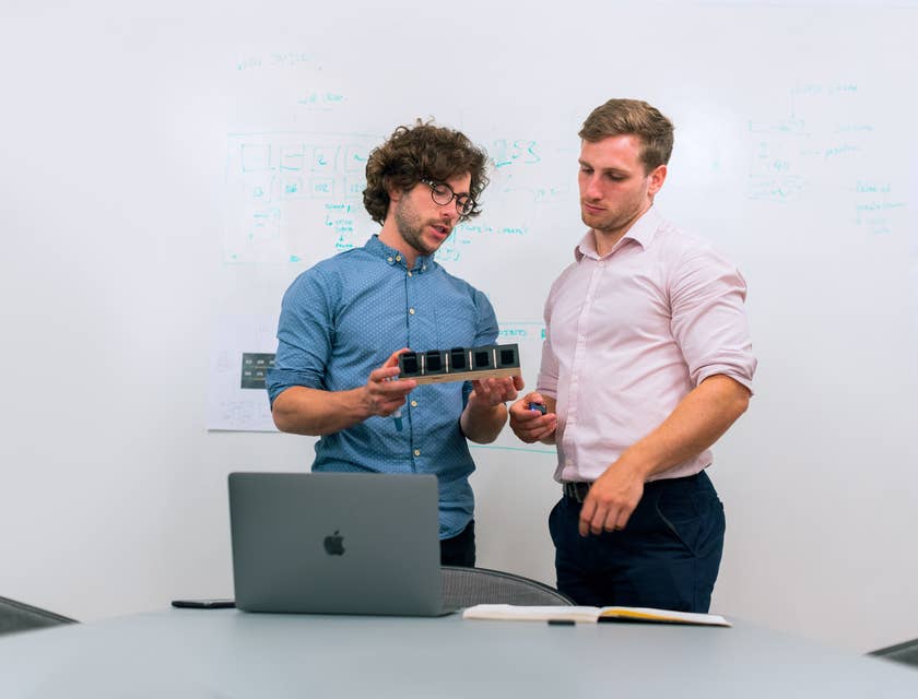 Two product development engineers discussing the product at hand while standing by the whiteboard.