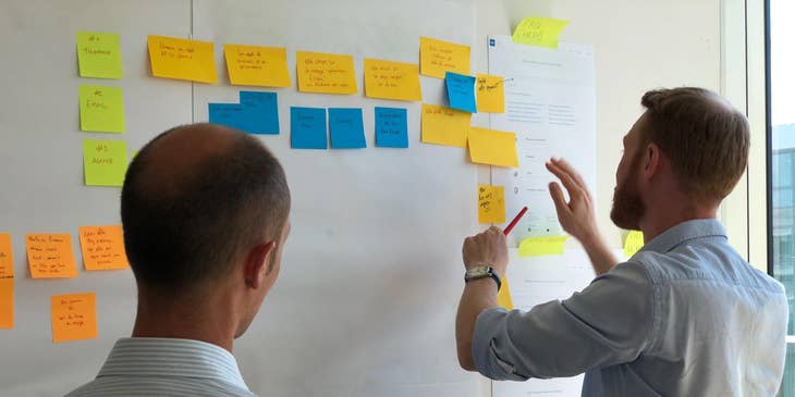 Product owner checking the development process of his project while his colleague is looking on.