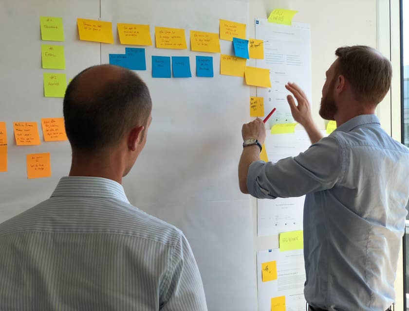 Product owner checking the development process of his project while his colleague is looking on.