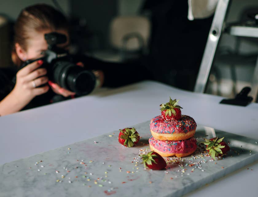 a product photographer taking photos of strawberry donuts for the newly opened doughnut shop