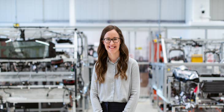 Female production engineer standing in workshop with the manufactured products behind her.