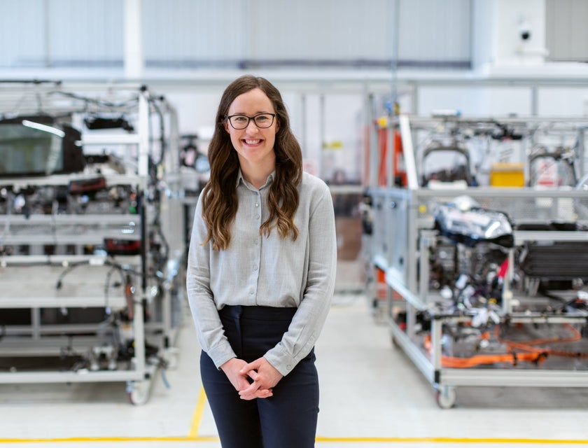 female production engineer standing in workshop with the manufactured products behind her
