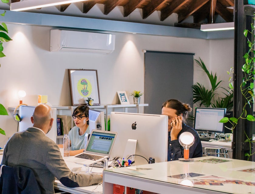 a team of programmer analysts discussing something while sitting at their respective workstations