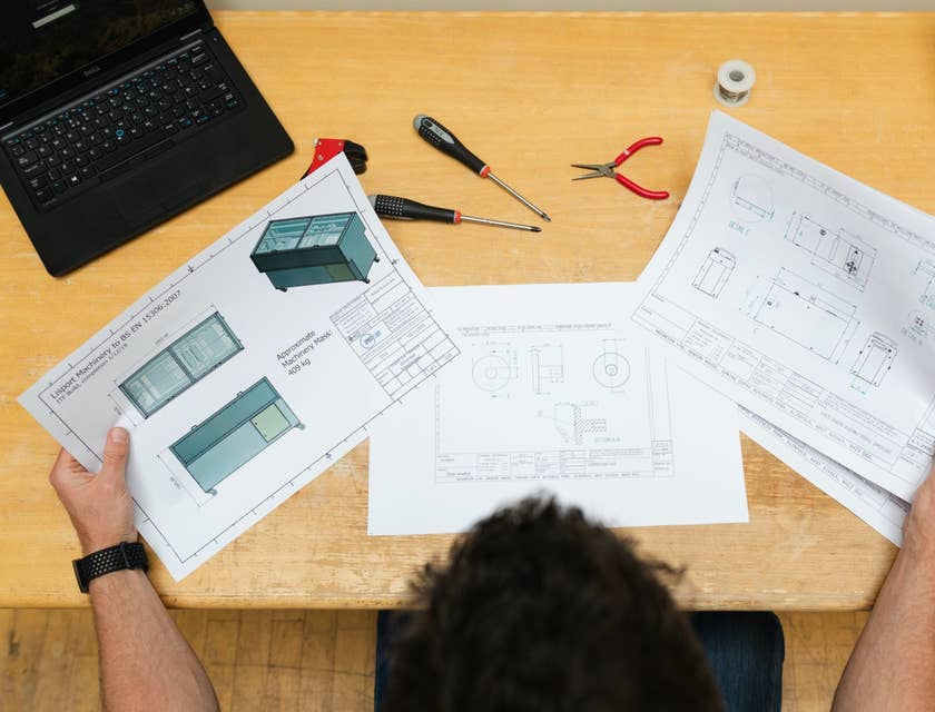 Project engineer holding and looking at the product plans on his desk