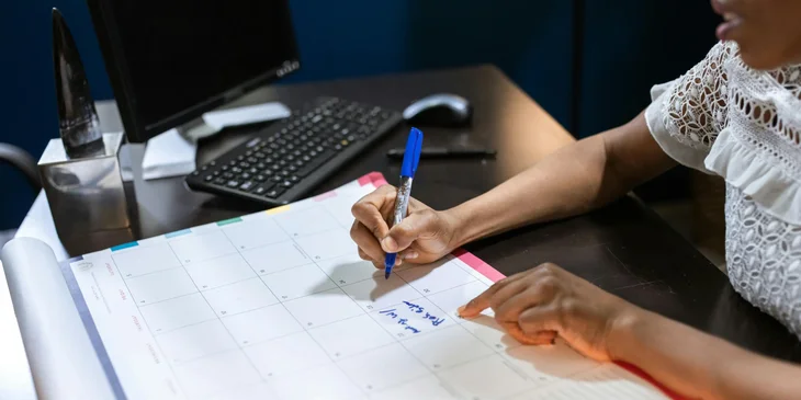 A project scheduler writing on an office calendar.