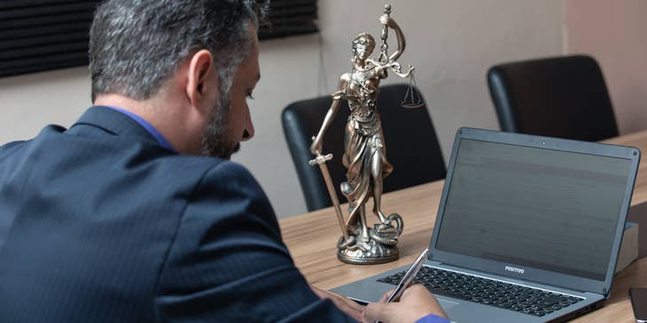 A Public Defender preparing his defense for a client in preparation for the trial while conducting some legal research on his laptop.