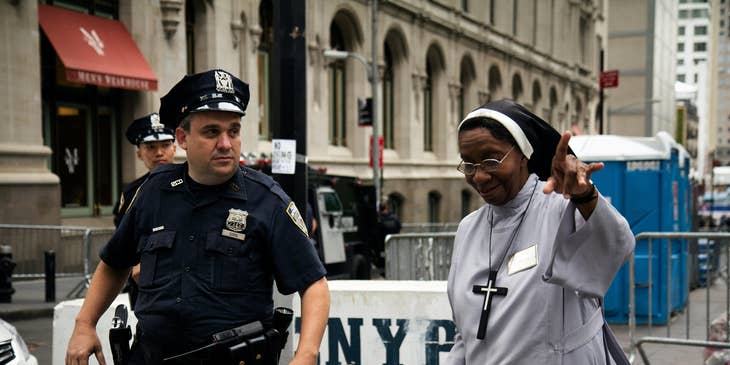 A public safety officer assisting a nun and ensuring peace and order are being maintained during a public gathering.