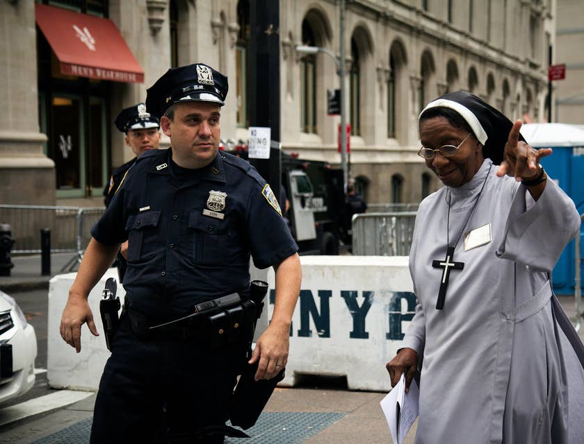 A public safety officer assisting a nun and ensuring peace and order are being maintained during a public gathering.