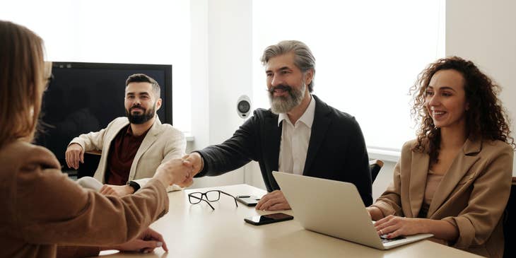 Tres colegas dan la bienvenida a un nuevo miembro a su equipo de reclutamiento.