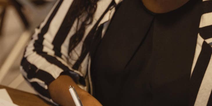 Woman sitting at a desk with a smartphone in her hand.