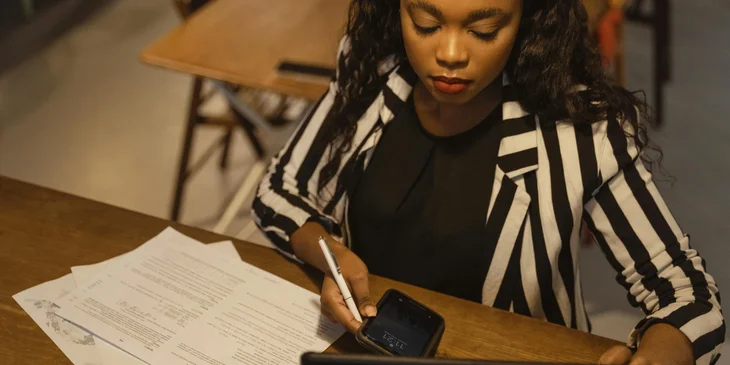 A woman sitting at a desk with a smartphone in her hand.